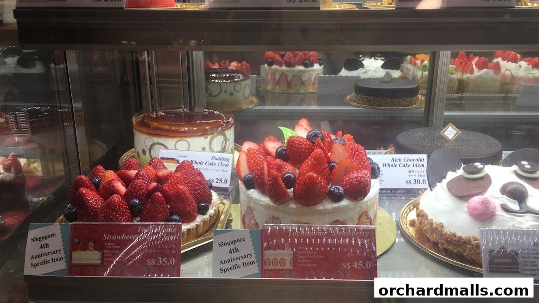 A display case filled with various cakes, including strawberry and chocolate varieties.