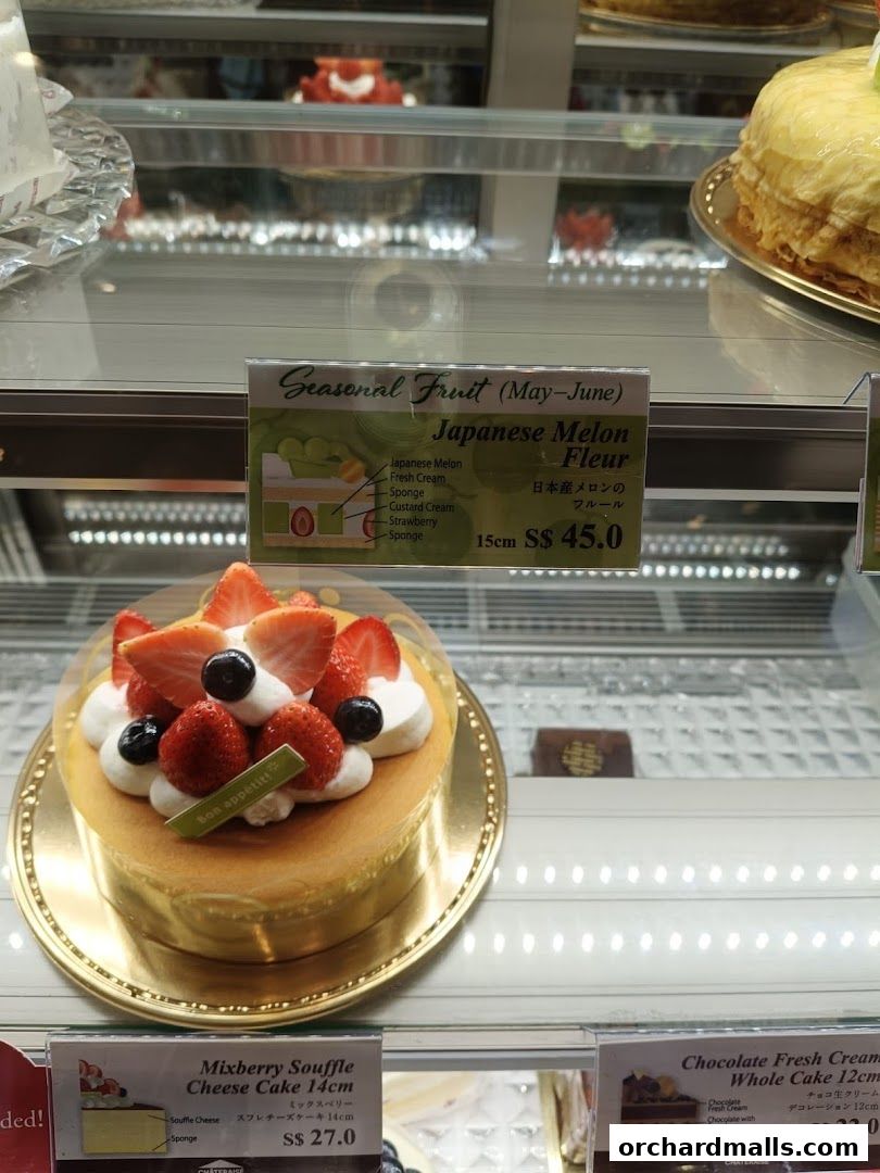 A display case filled with delicious cakes, featuring a strawberry-topped cake and a Japanese Melon cake.
