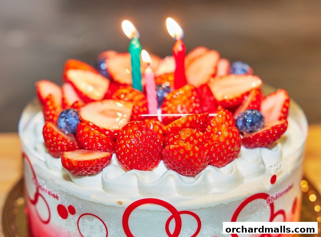 A close-up of a delicious strawberry and blueberry cake with lit birthday candles.