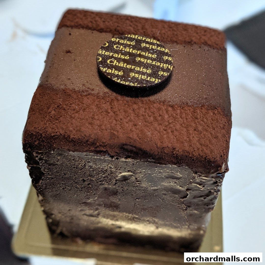 A close-up of a rich chocolate cake with a Châteraisé logo on top.