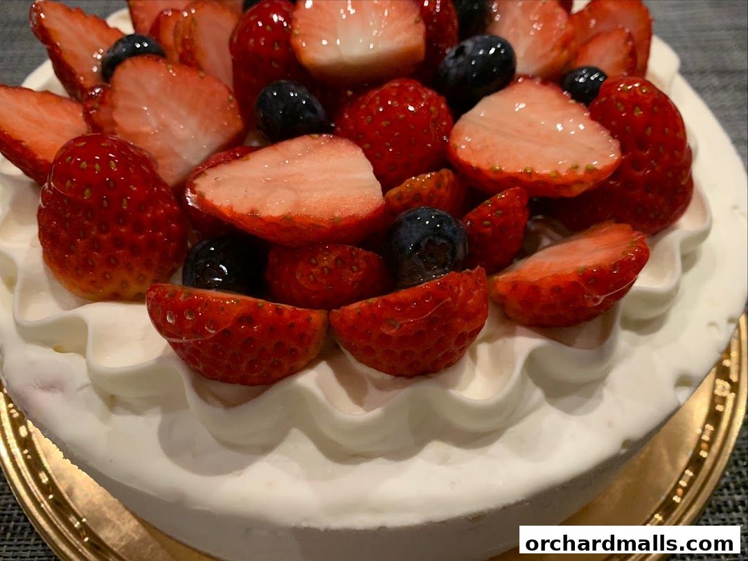 A close-up of a delicious cake topped with fresh strawberries and blueberries.