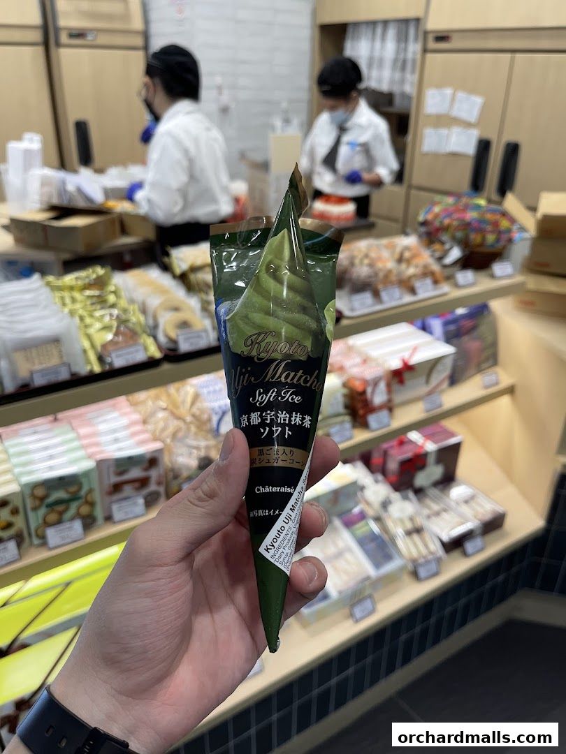 A hand holds a Kyoto Uji Matcha soft-serve ice cream cone from Châteraisé.