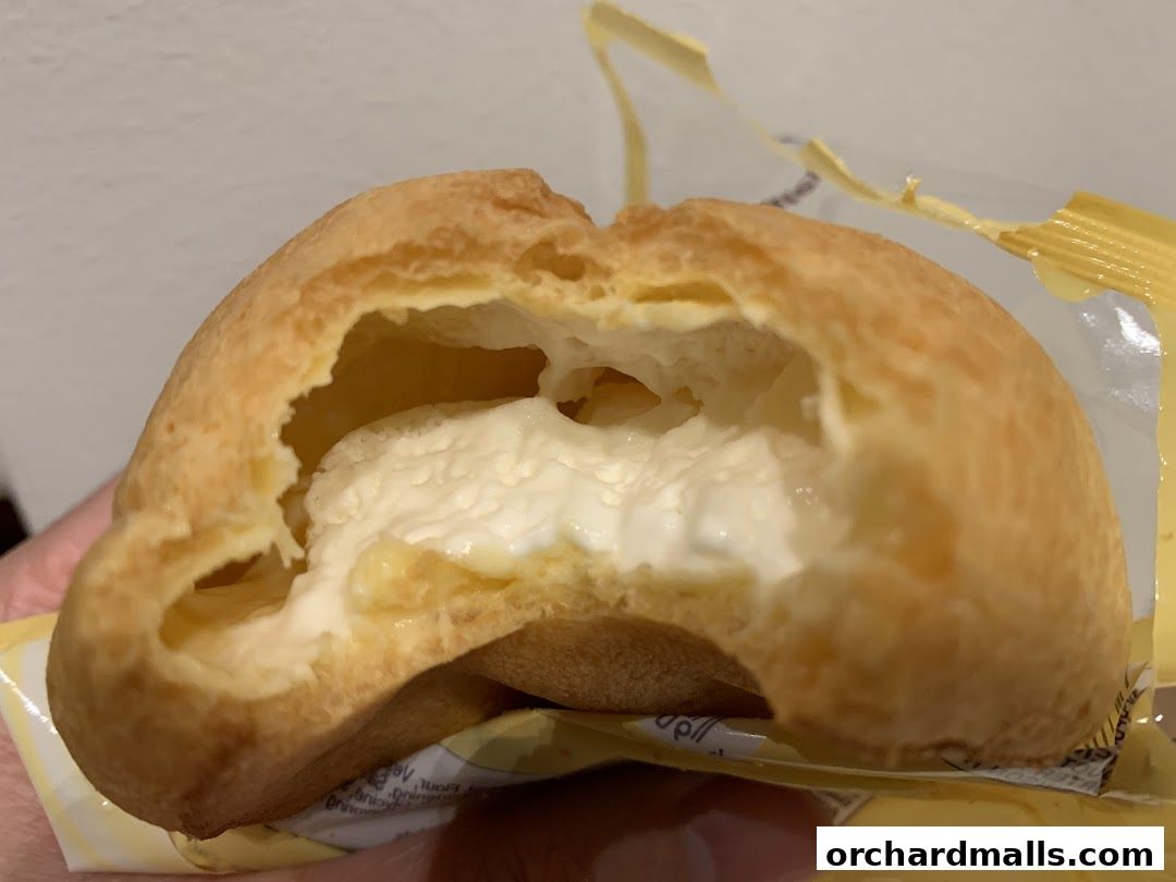 A close-up shot of a cream puff pastry, split open to reveal a creamy filling.