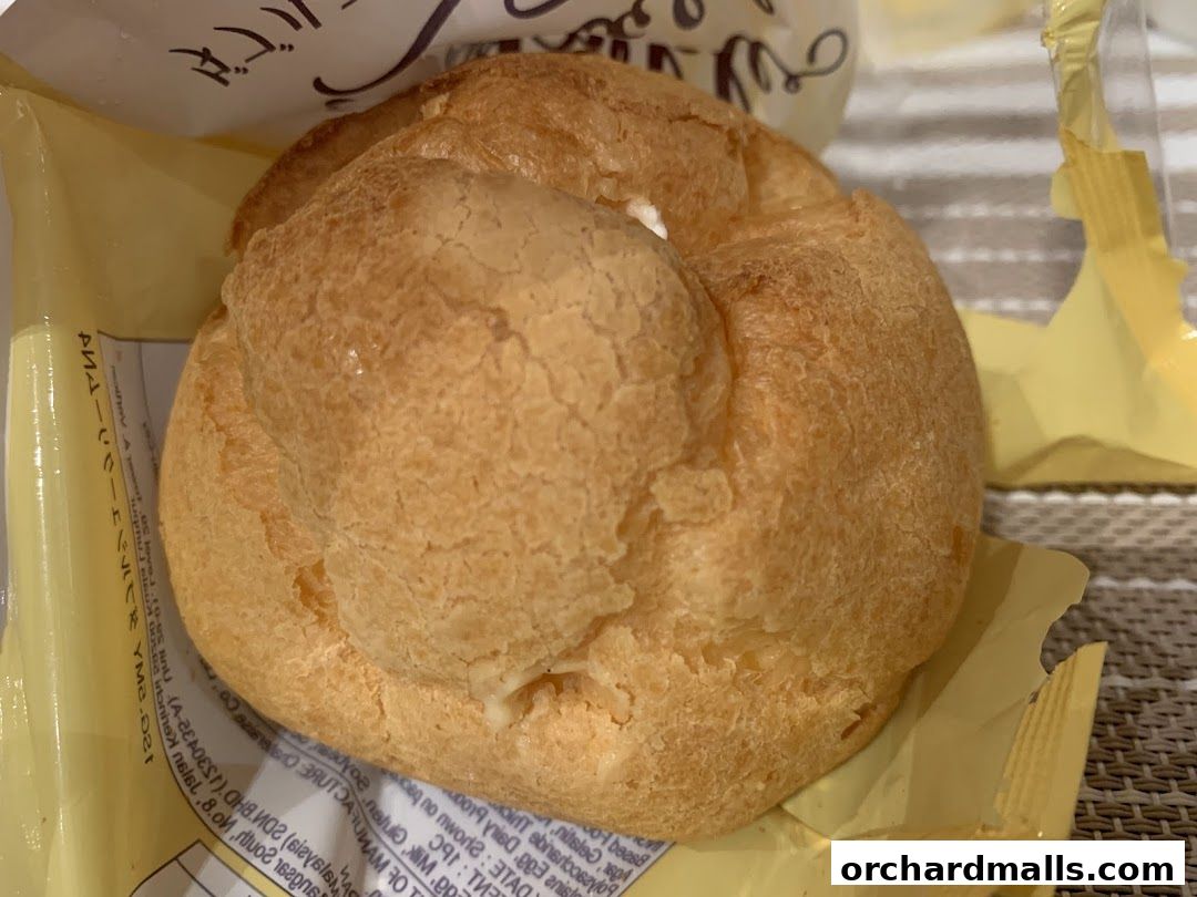 A close-up of a golden-brown cream puff pastry with visible cream filling.