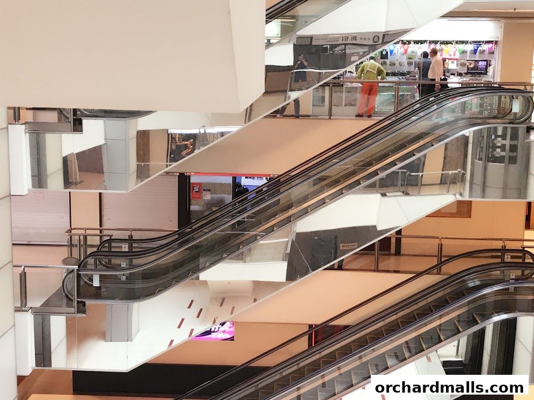 Reflections of escalators and shop fronts in a modern shopping mall.