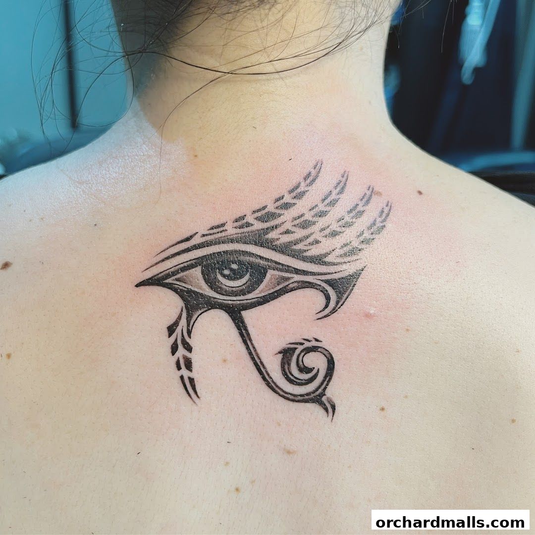 A close-up of an Egyptian Eye of Horus tattoo on a person's upper back.