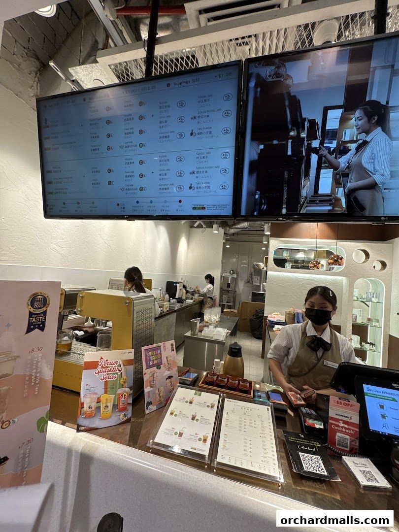 A view of the counter at CHICHA San Chen with staff and digital menus.