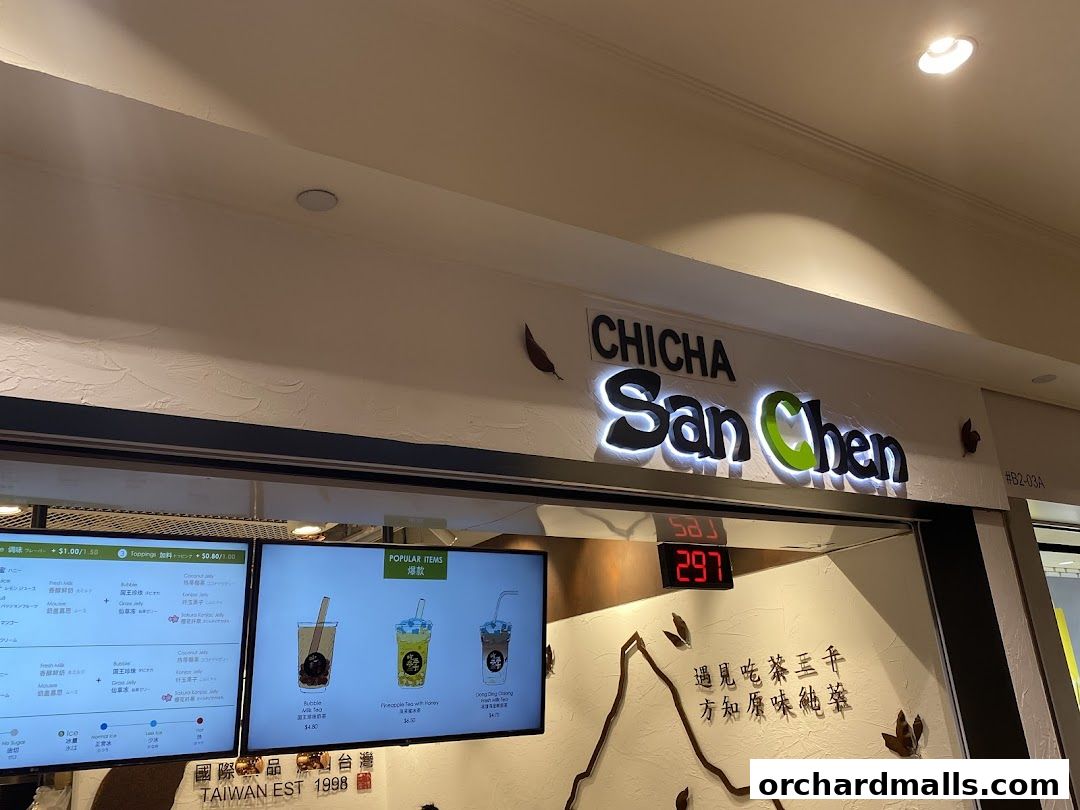 The exterior of CHICHA San Chen, a bubble tea shop, with its illuminated sign and digital menu screens.