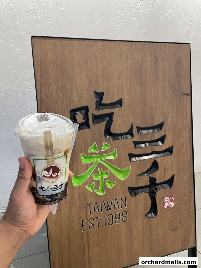 A hand holds a bubble tea in front of a CHICHA San Chen sign.