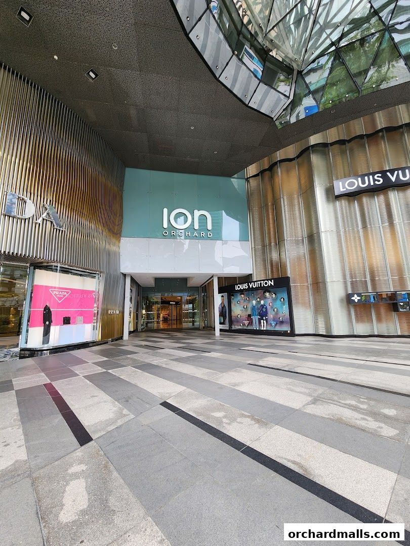 Exterior view of ION Orchard mall entrance with Prada and Louis Vuitton storefronts.