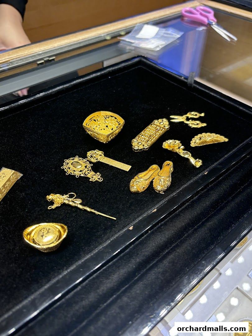 A display of intricate gold jewelry pieces, including a fan, abacus, and tiny shoes.