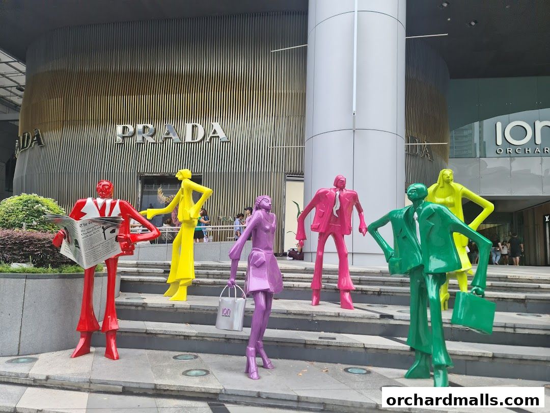 Colorful sculptures of people in business attire stand outside the Prada store at ION Orchard.