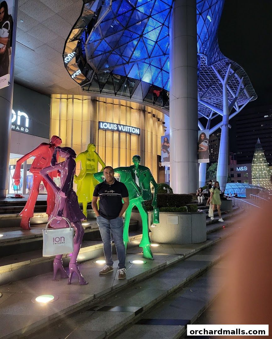 A man poses with colorful sculptures in front of the Louis Vuitton store at ION Orchard.