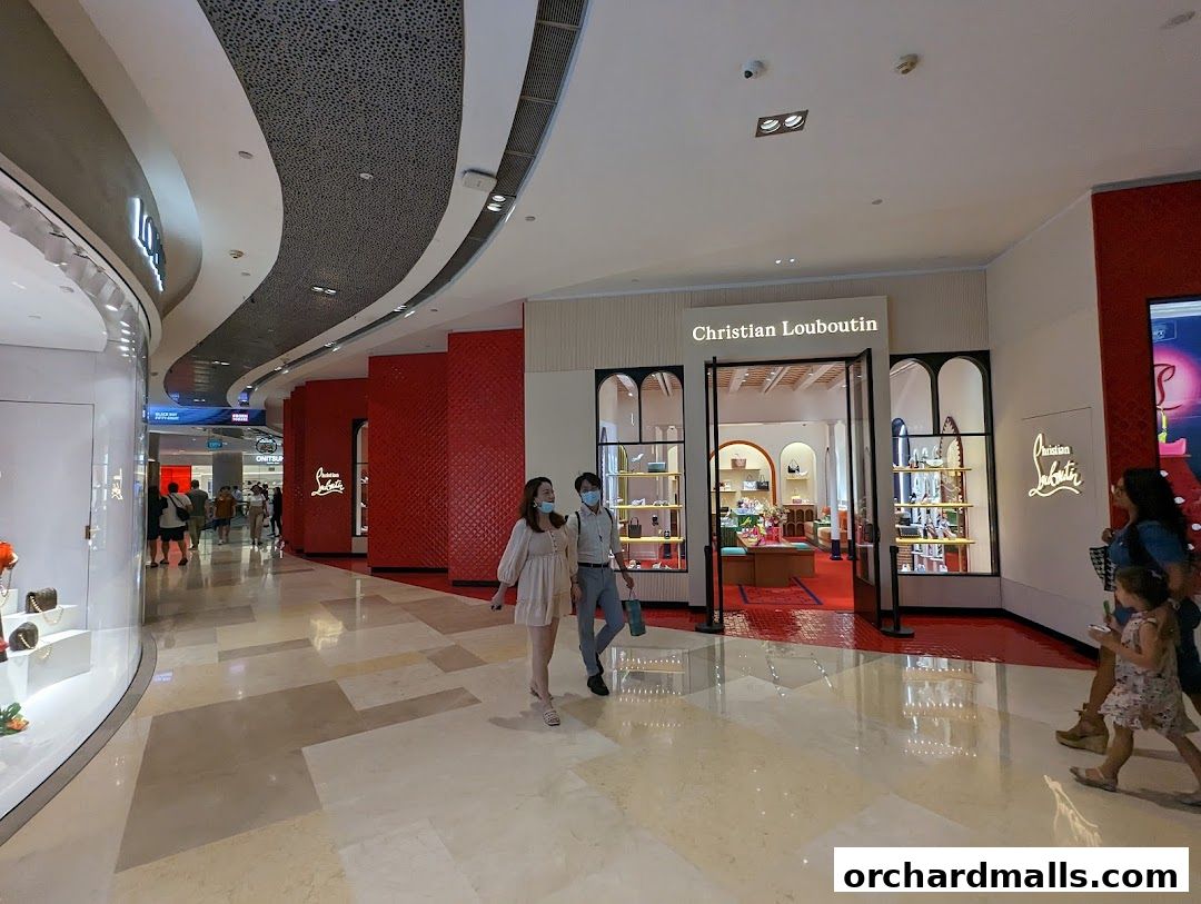 The Christian Louboutin store entrance with display windows and people walking by.