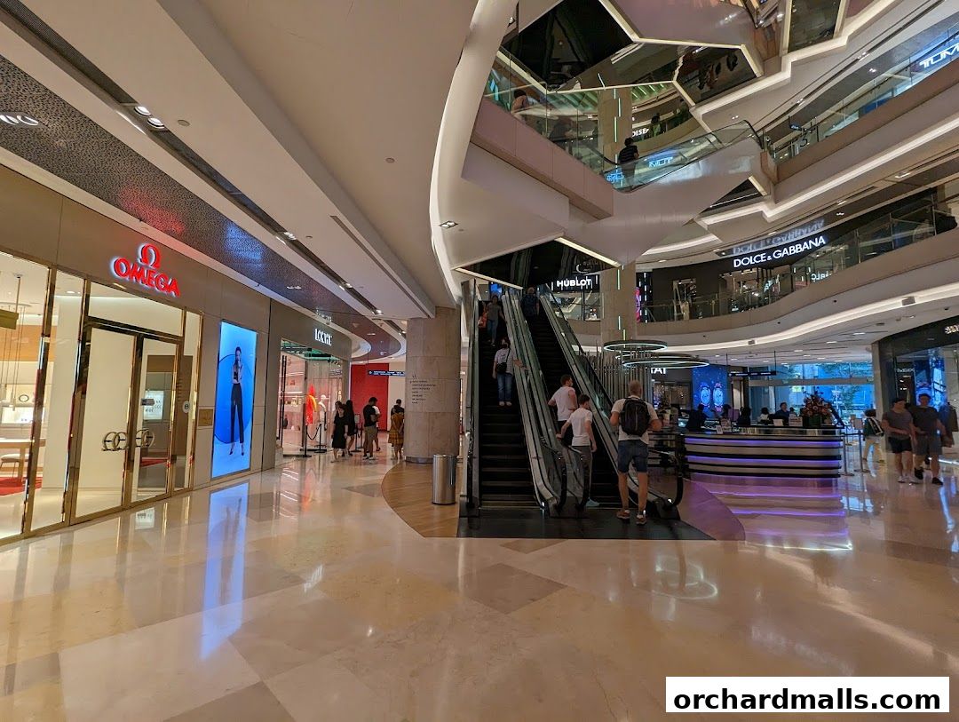 Interior view of a luxury shopping mall with escalators and various high-end stores.