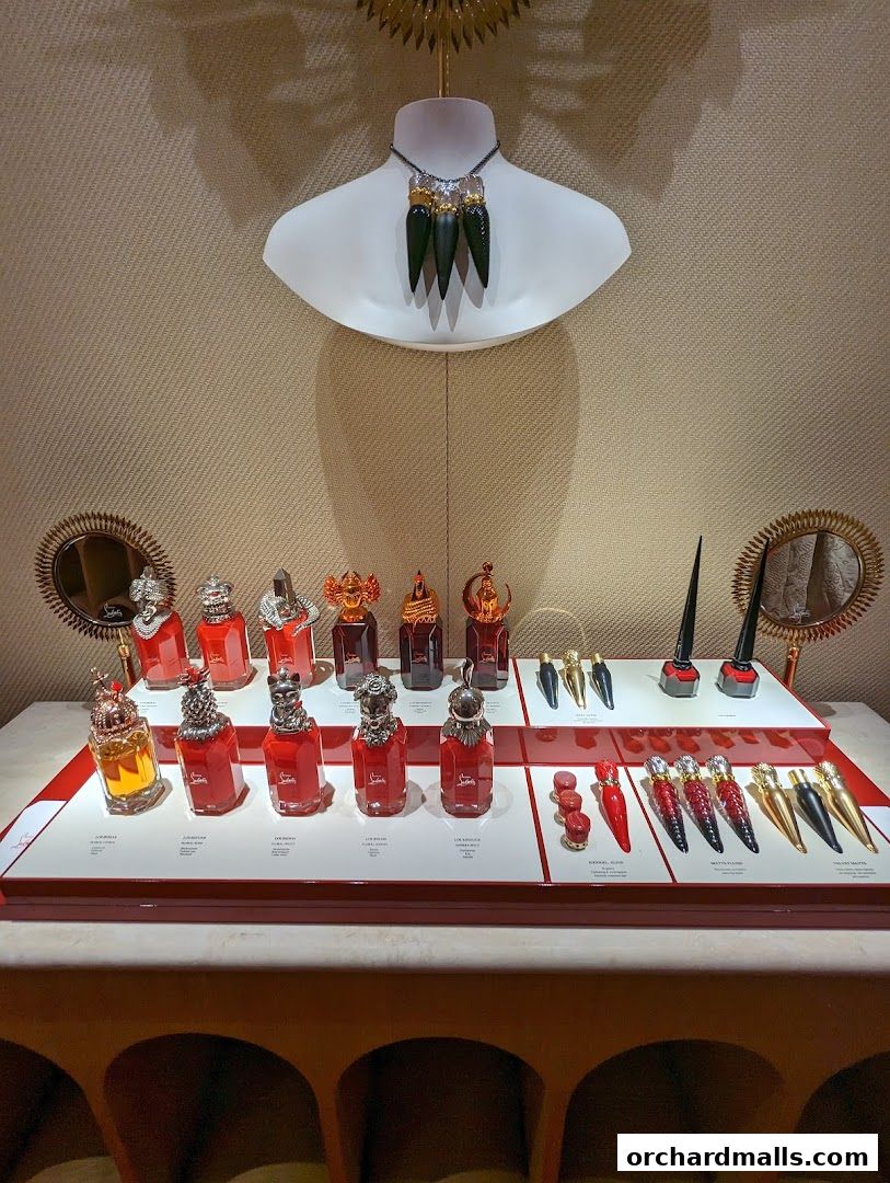 A display of Christian Louboutin perfumes and lipsticks on a white tiered stand.