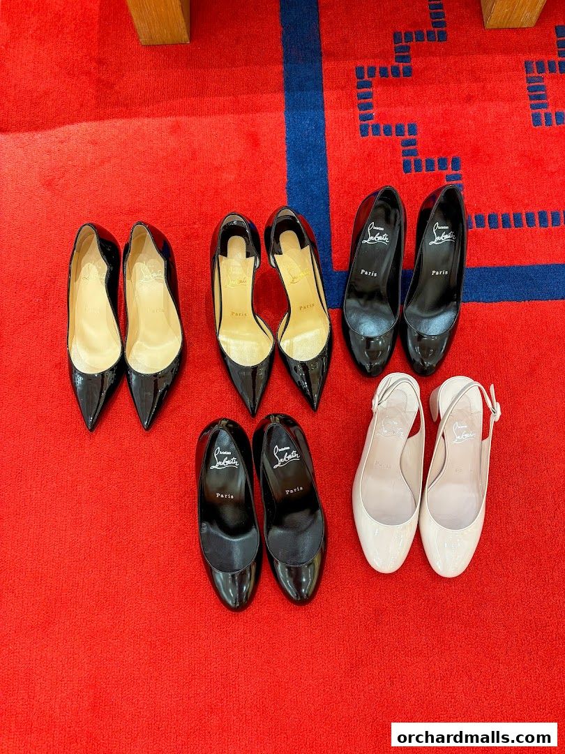 A collection of Christian Louboutin high heels and flats displayed on a red carpet.