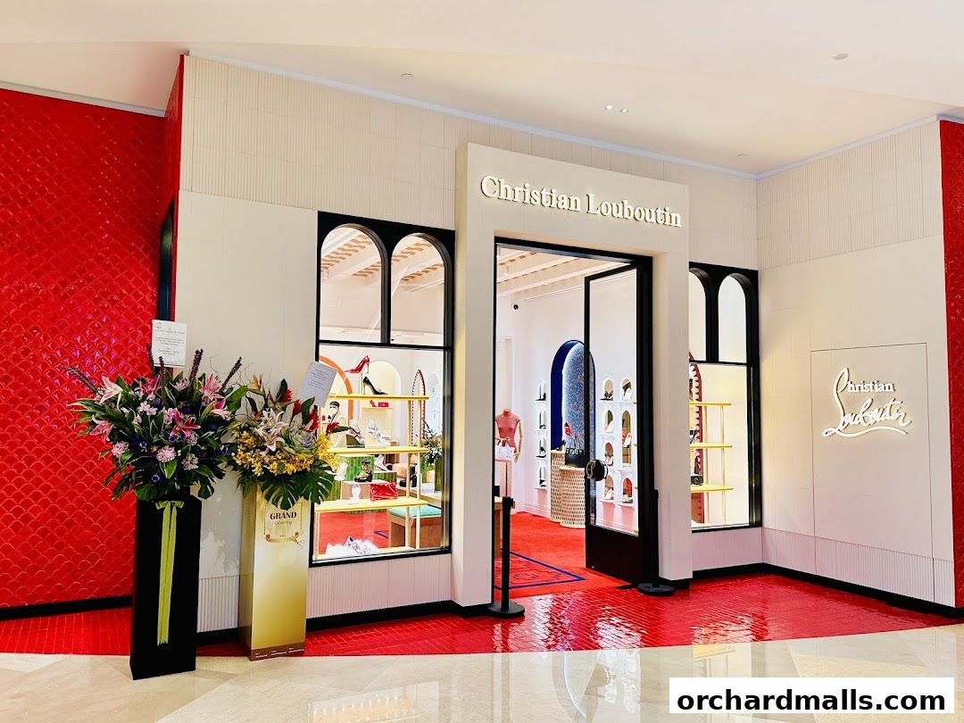 The entrance of the Christian Louboutin Singapore ION Orchard store, featuring floral arrangements and the iconic red sole.