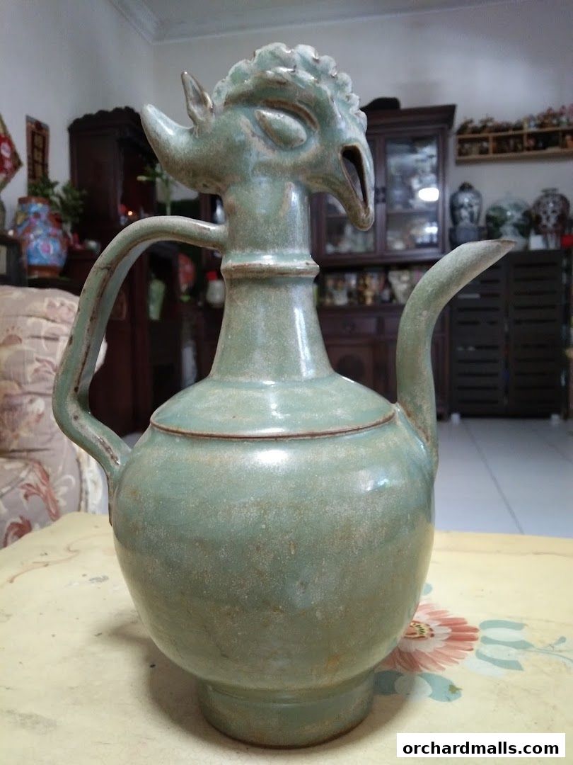 A vintage celadon ceramic pitcher with a bird-like spout and handle.