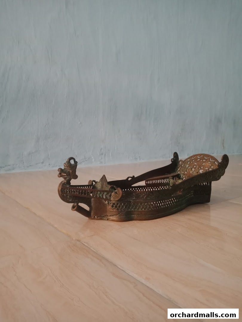 An ornate brass antique ship-shaped decorative item with intricate carvings.