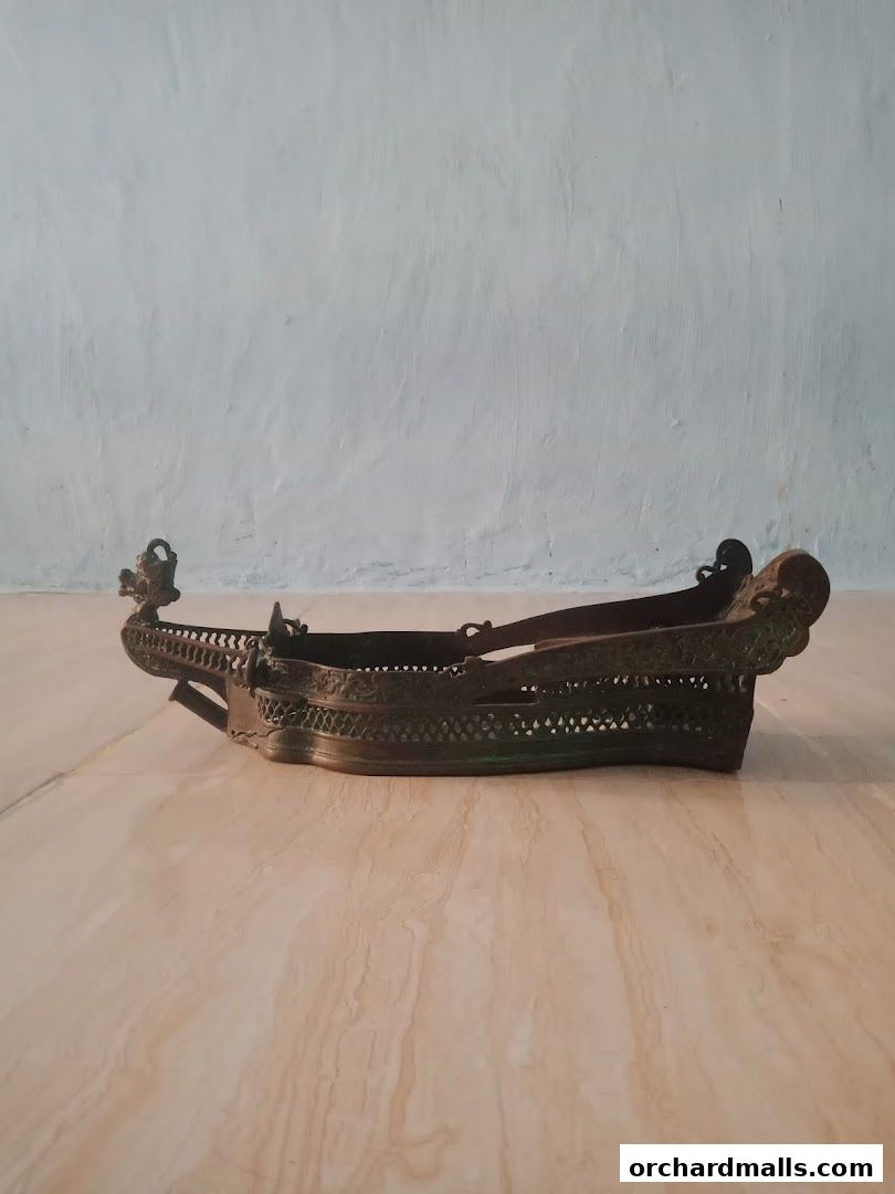 An antique brass decorative boat-shaped tray with intricate carvings.