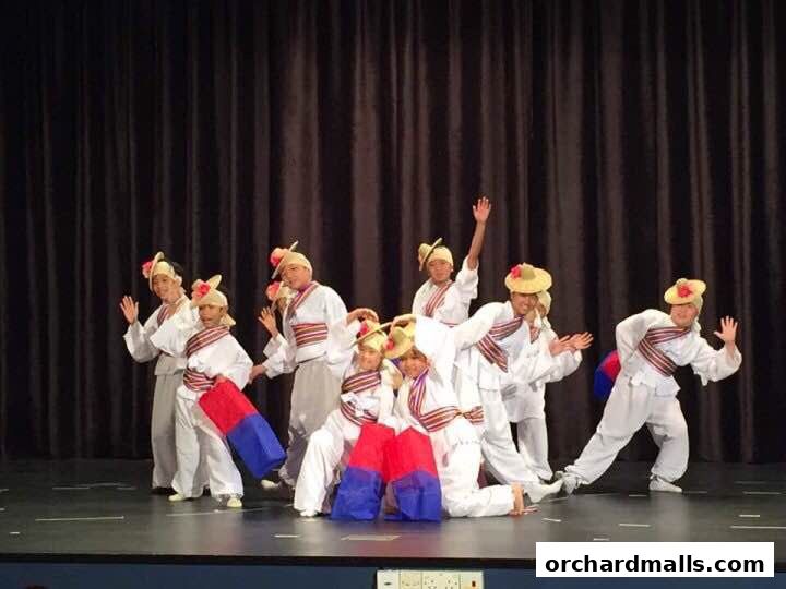 A group of performers in traditional white and red costumes on a stage.