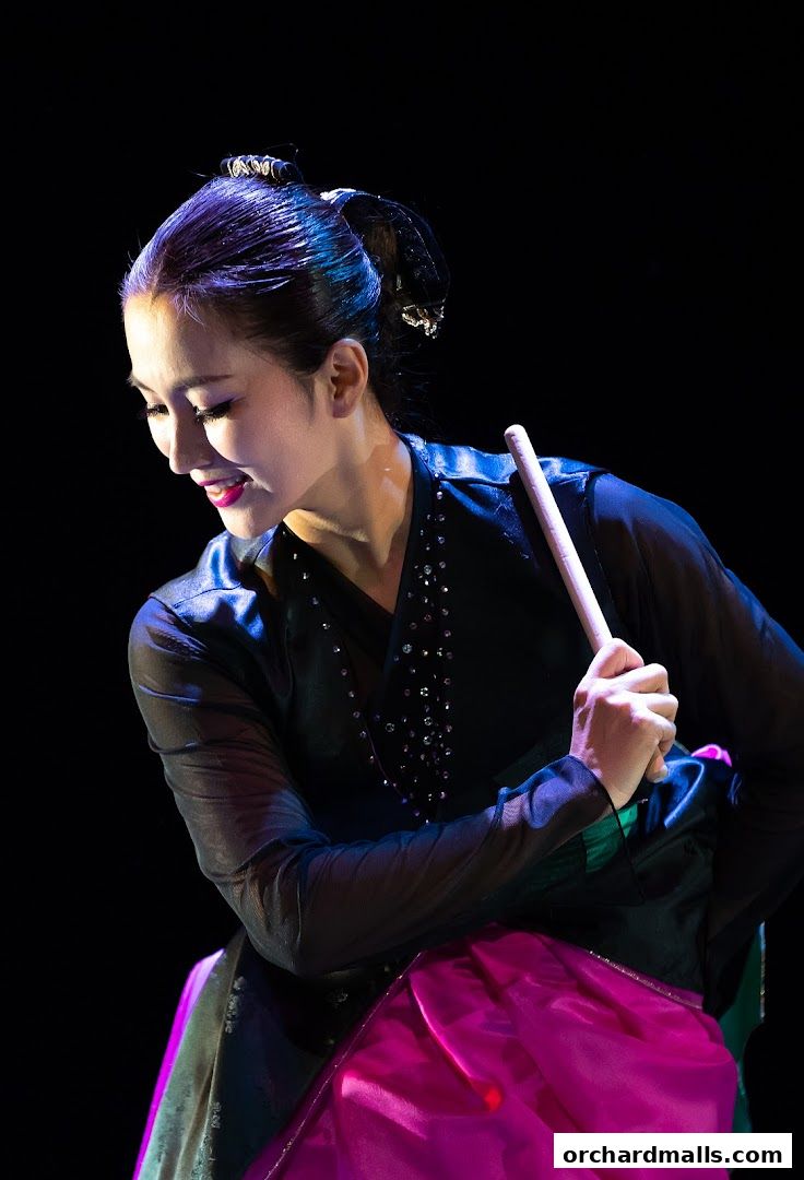 A woman in traditional attire performs a dance with a stick.