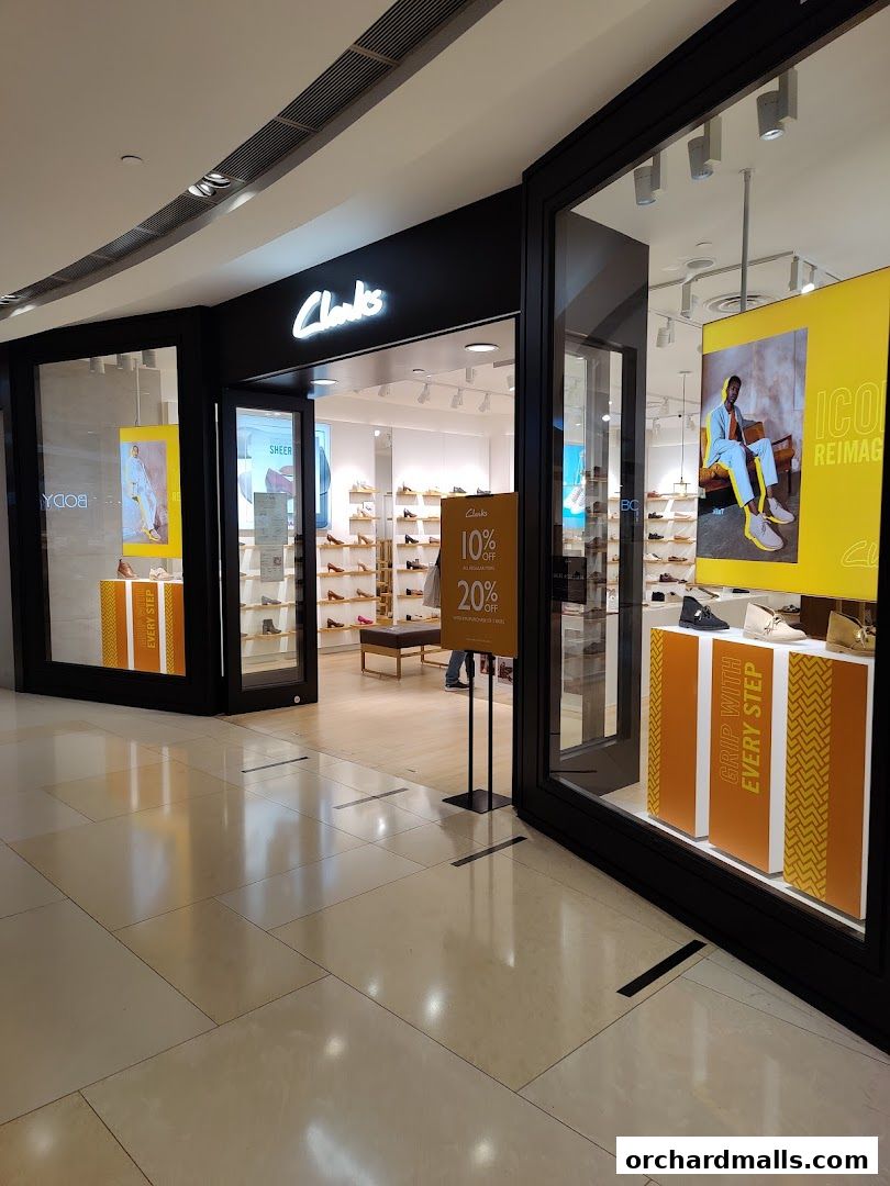 The entrance to a Clarks shoe store with displays of shoes and promotional signage.