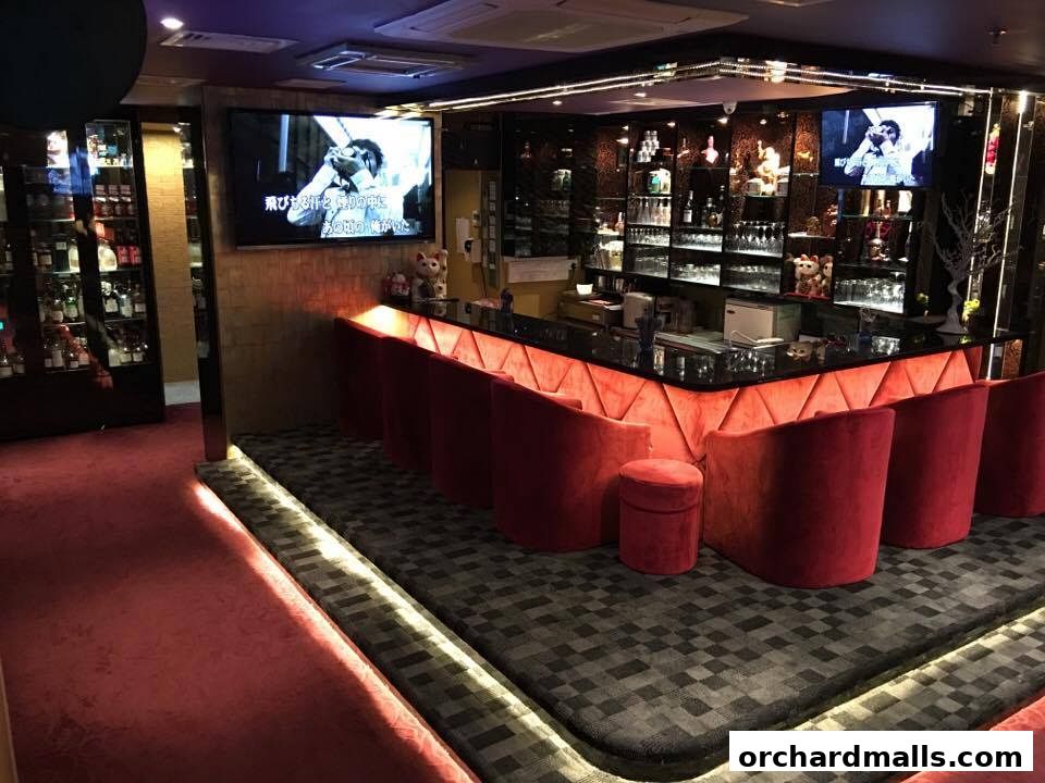 Interior of a stylish bar with red velvet seating and a well-stocked bar.
