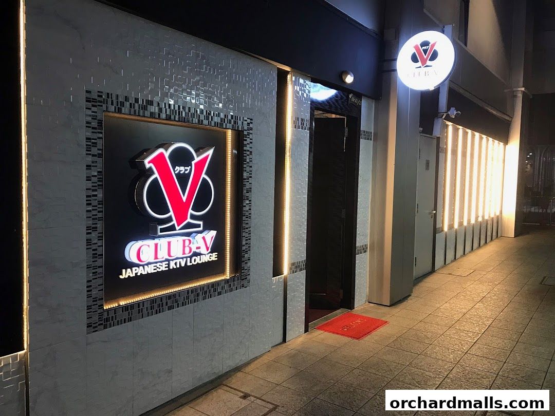The exterior of CLUB-V Japanese KTV Lounge at night, with illuminated signage and entrance.