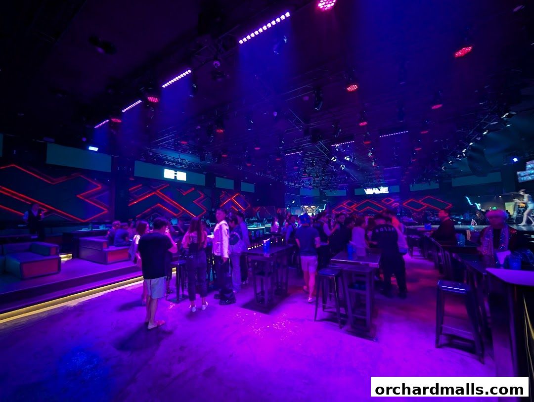 Interior of a vibrant nightclub with neon lights, seating areas, and patrons.