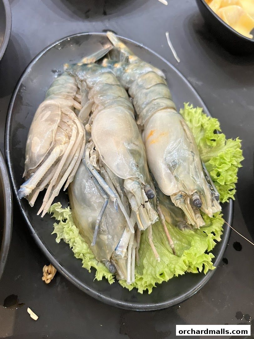 A plate of three large, raw prawns served on a bed of lettuce.