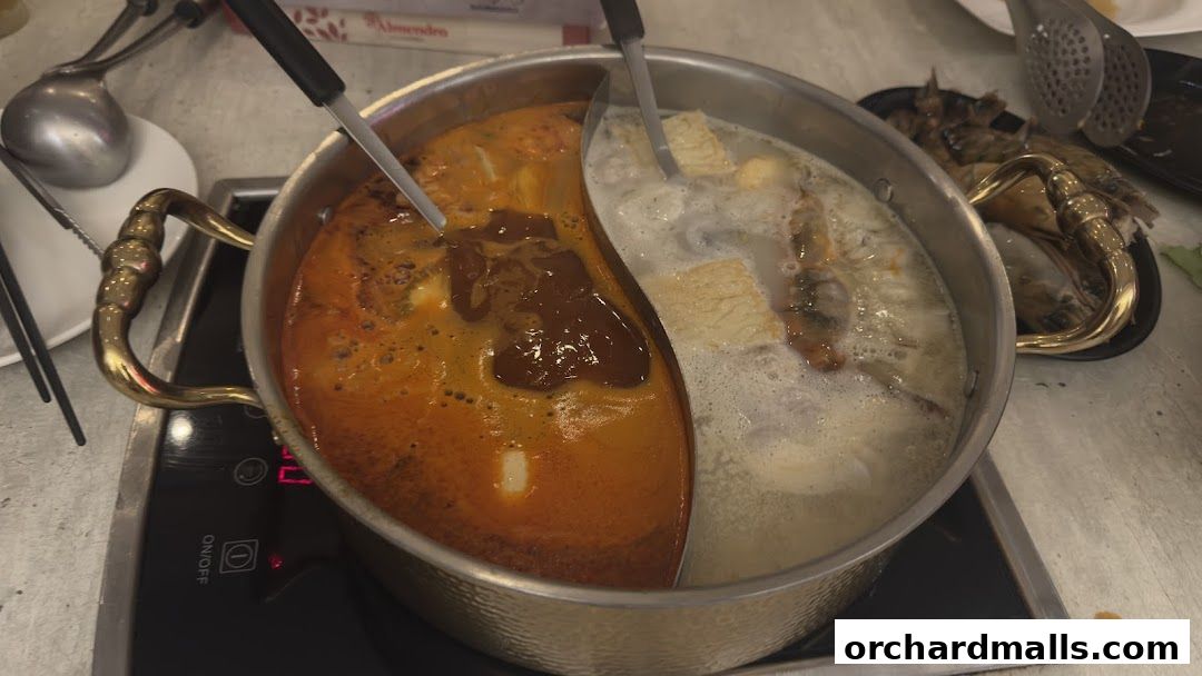 A split hot pot with two different broths and ingredients simmering.
