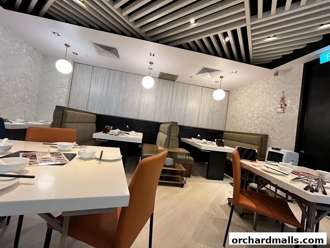 Interior of a modern restaurant with white tables, orange chairs, and booth seating.