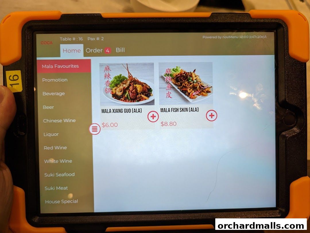 A tablet displaying a digital menu for COCA restaurant, featuring Mala Favourites.