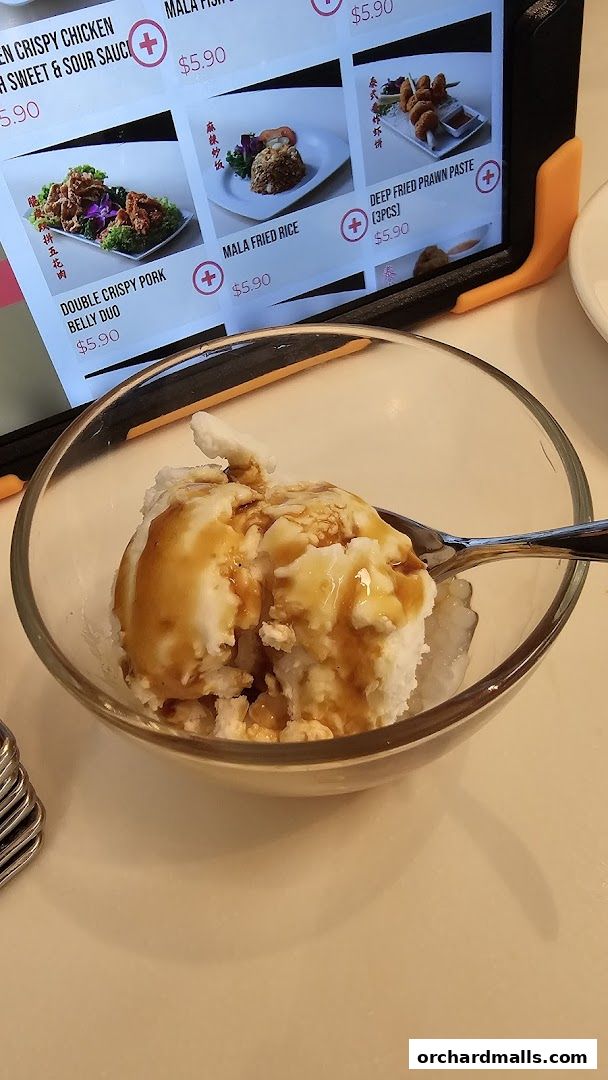 A digital menu displays various dishes with prices, next to a bowl of dessert.
