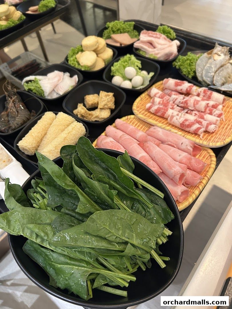 A variety of fresh ingredients for hot pot, including meats, seafood, vegetables, and tofu.