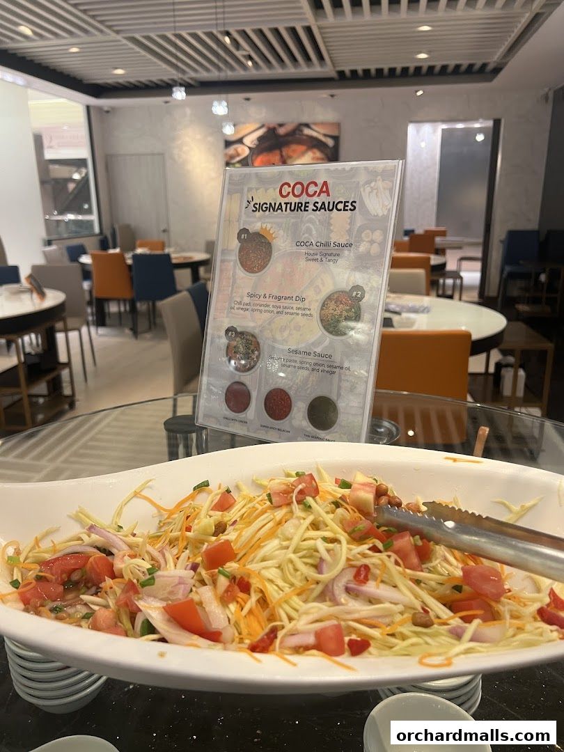 A sign displaying COCA signature sauces with a salad in the foreground.