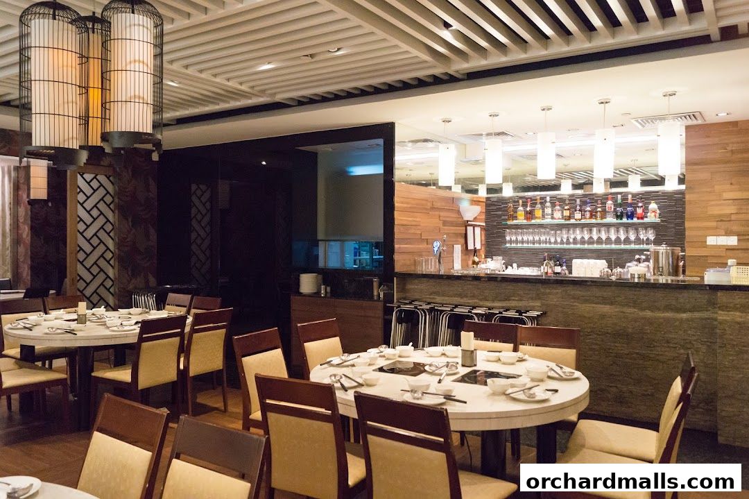Interior of a restaurant with round tables set for dining and a bar area.