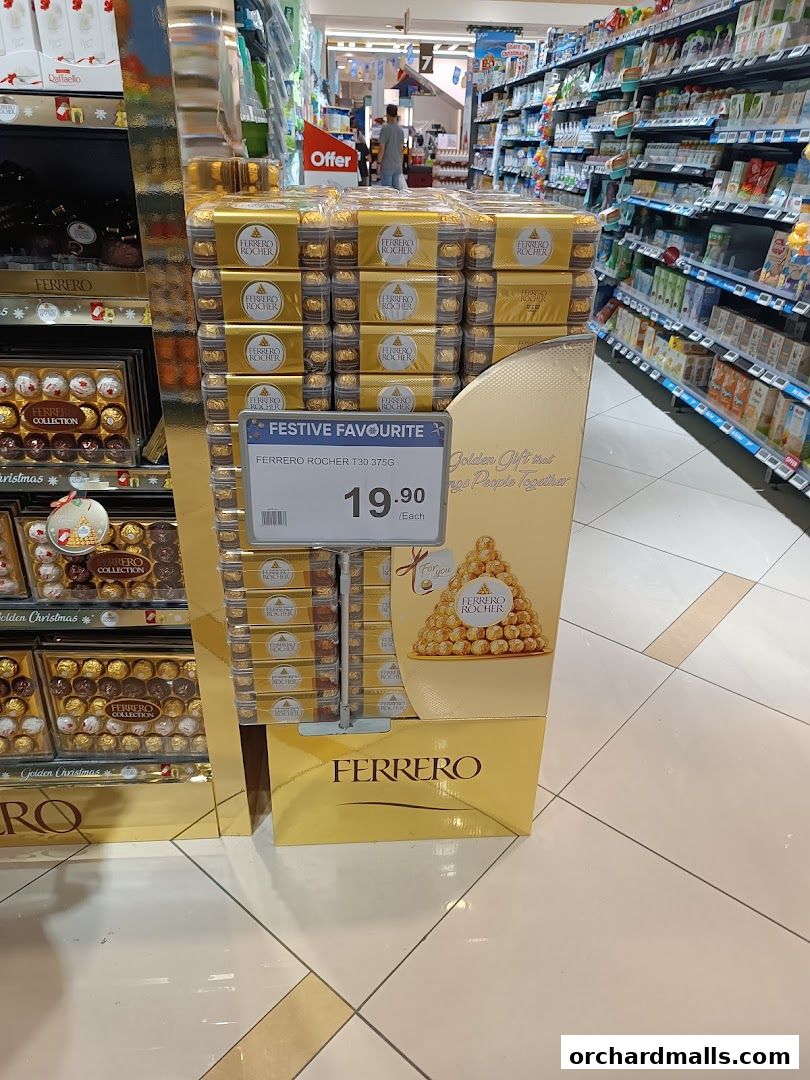A display of Ferrero Rocher chocolates in a store, with a price tag and festive packaging.