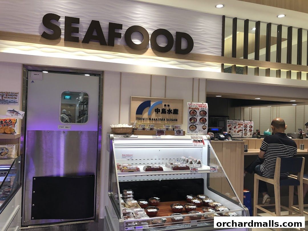 A seafood shop with a display of fresh seafood and a counter with customers.