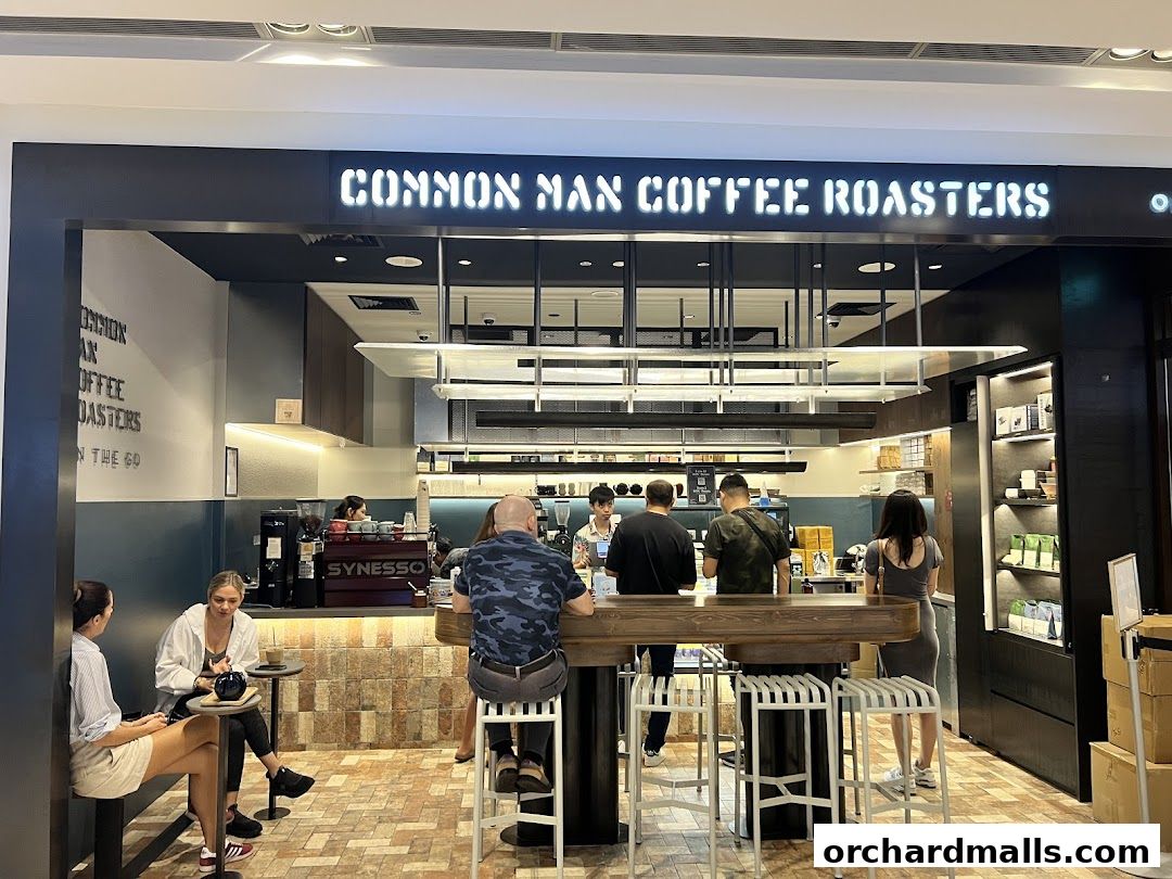People enjoying coffee at Common Man Coffee Roasters, a modern cafe with a prominent sign.