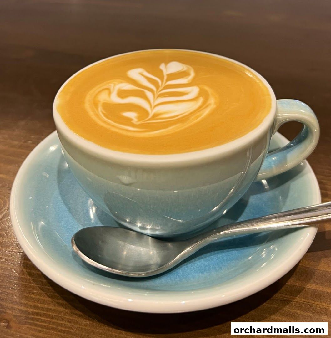 A close-up of a latte with intricate latte art in a light blue cup and saucer.