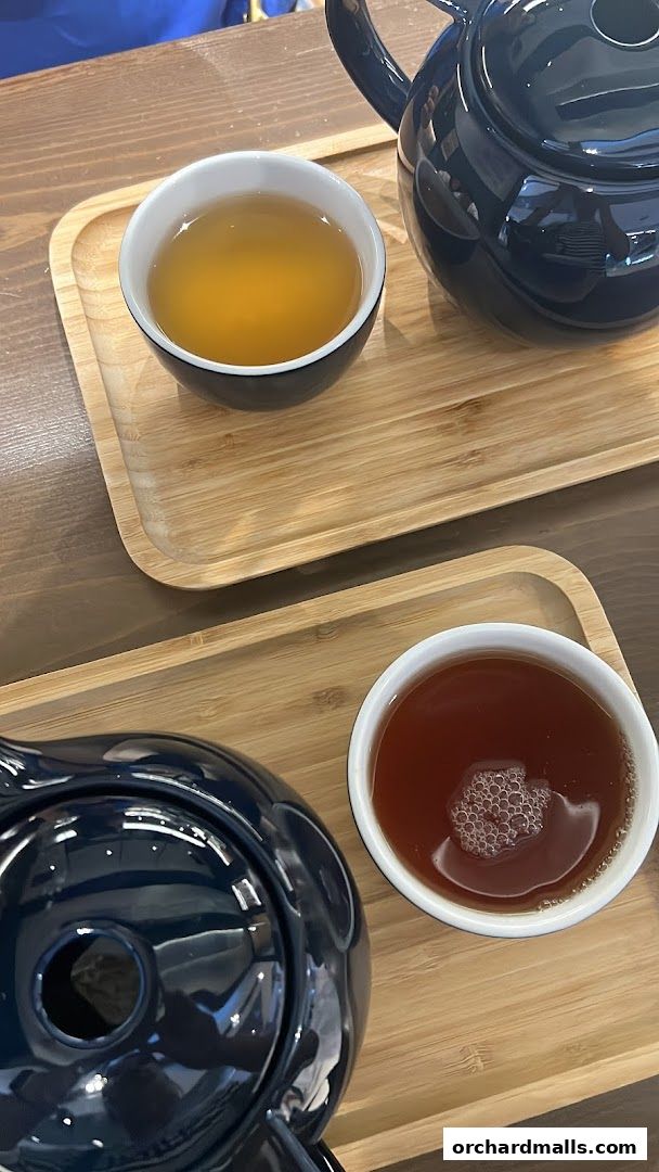 Two cups of tea and teapots served on wooden trays.