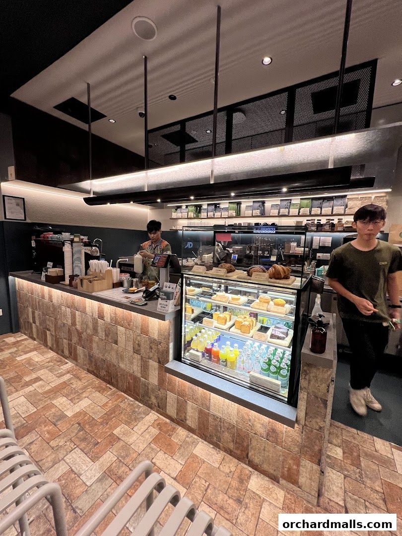 Interior of a coffee shop with a display case of pastries and drinks, and staff behind the counter.