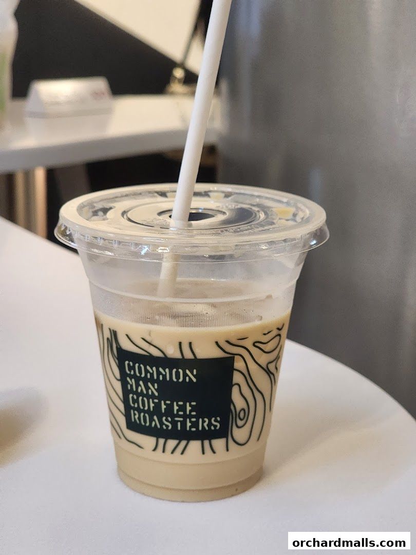 A refreshing iced coffee from Common Man Coffee Roasters with their logo on the cup.