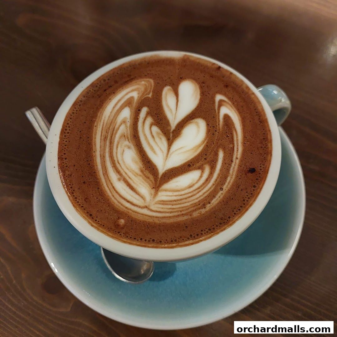 A close-up of a hot chocolate with latte art on a wooden table.