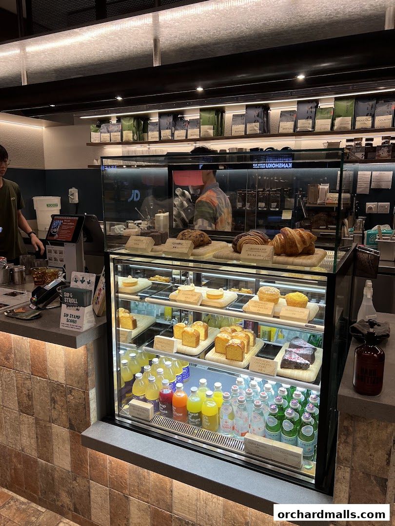 A display case filled with pastries, cakes, and bottled drinks at a coffee shop.