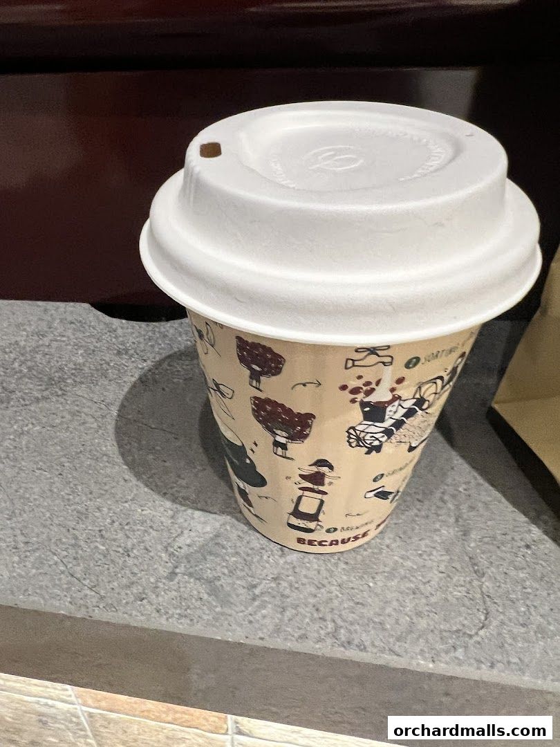 A paper coffee cup with a white lid and a patterned design.