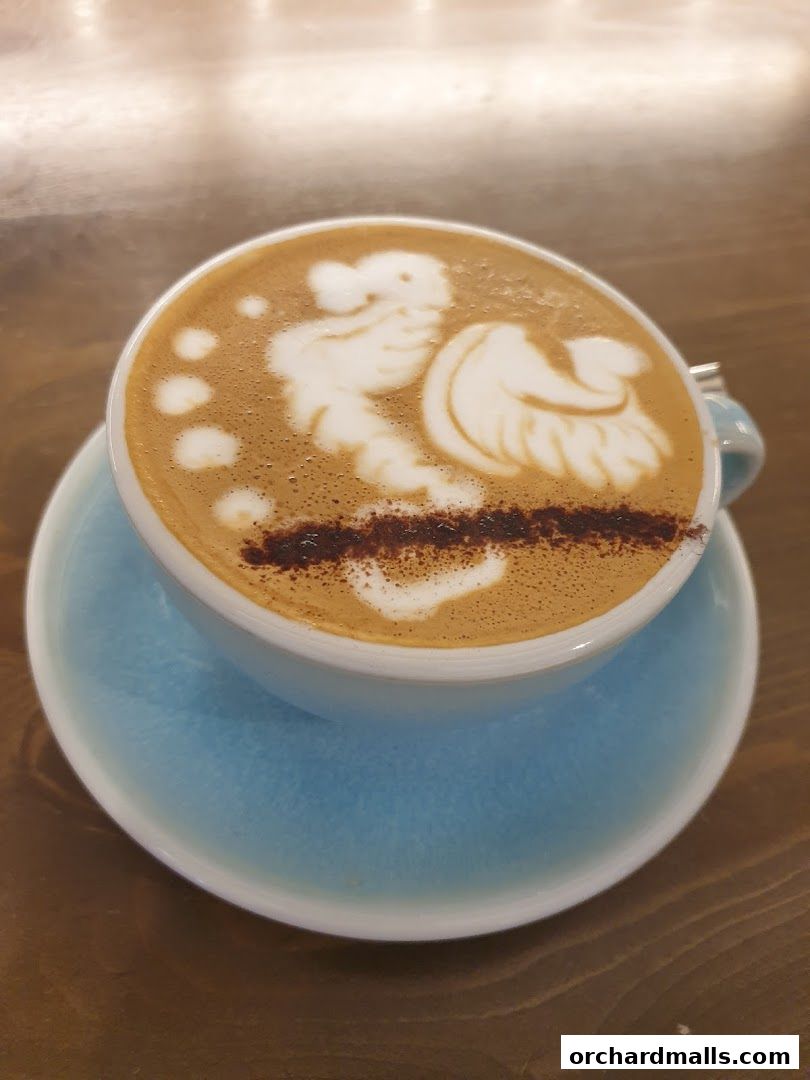 A close-up of a latte with intricate latte art featuring a bird design.